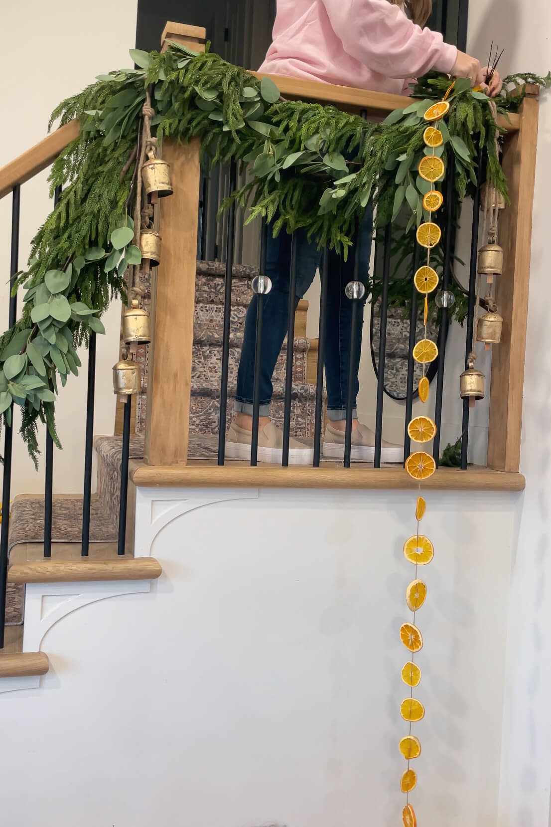 Hanging an orange slice garland on a stair banister.